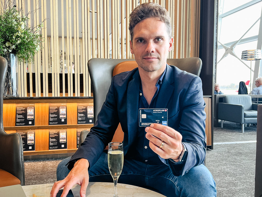 a man sitting in a chair holding a credit card and a glass of champagne